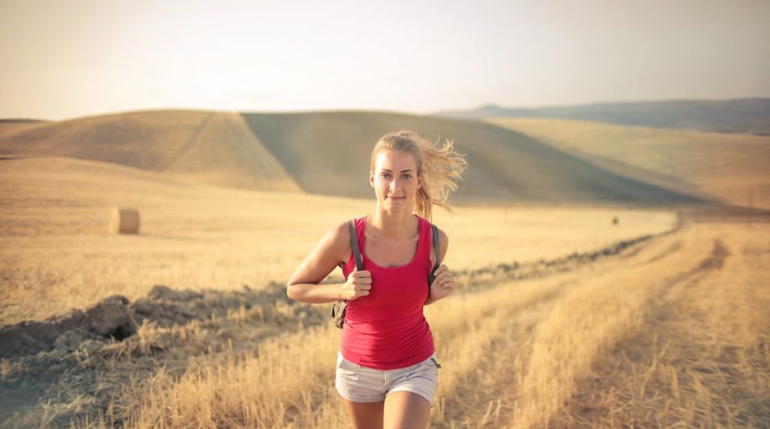 A woman jogging through vast, golden wheat fields under the summer sun, symbolizing freedom and adventure.