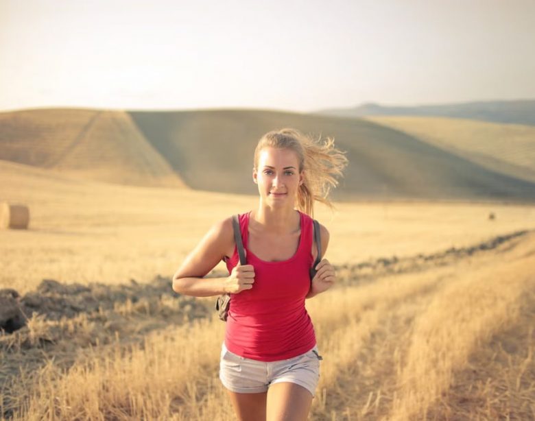 A woman jogging through vast, golden wheat fields under the summer sun, symbolizing freedom and adventure.
