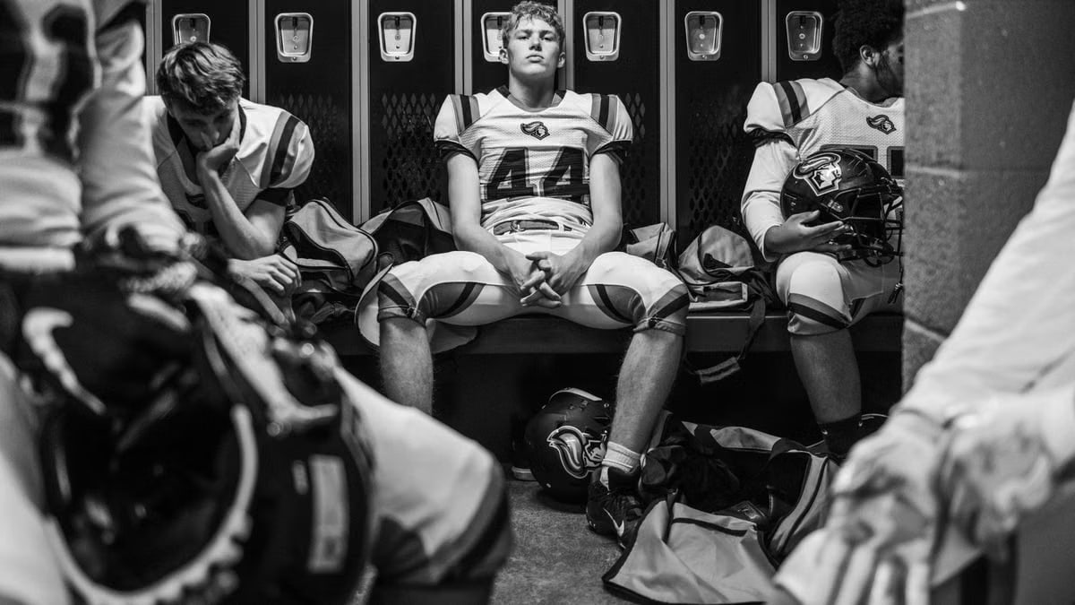 Intense black and white photo captures high school football players in a locker room pre-game.